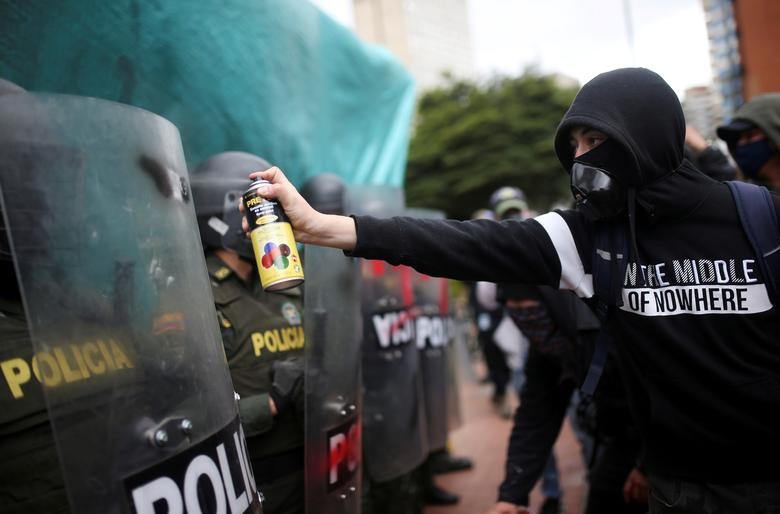 A demonstrator sprays a riot police shield during a protest in Bogota, Colombia. REUTERS/Luisa Gonzalez  